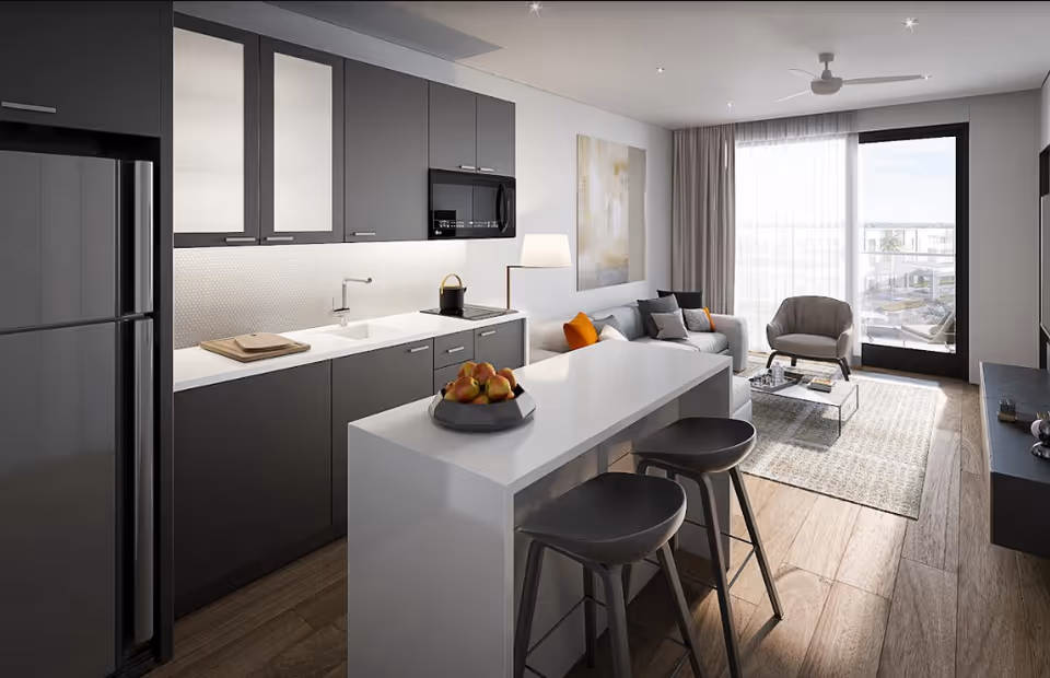 Open-plan modern kitchen and living room with a white island and stools, sofa and armchair facing a large window/door to a balcony.