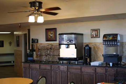Dining area with beverage machines, a counter, and round tables under a ceiling fan.