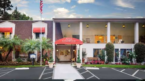 Front view of Atria Collwood senior living facility entrance with red canopy and landscaping.