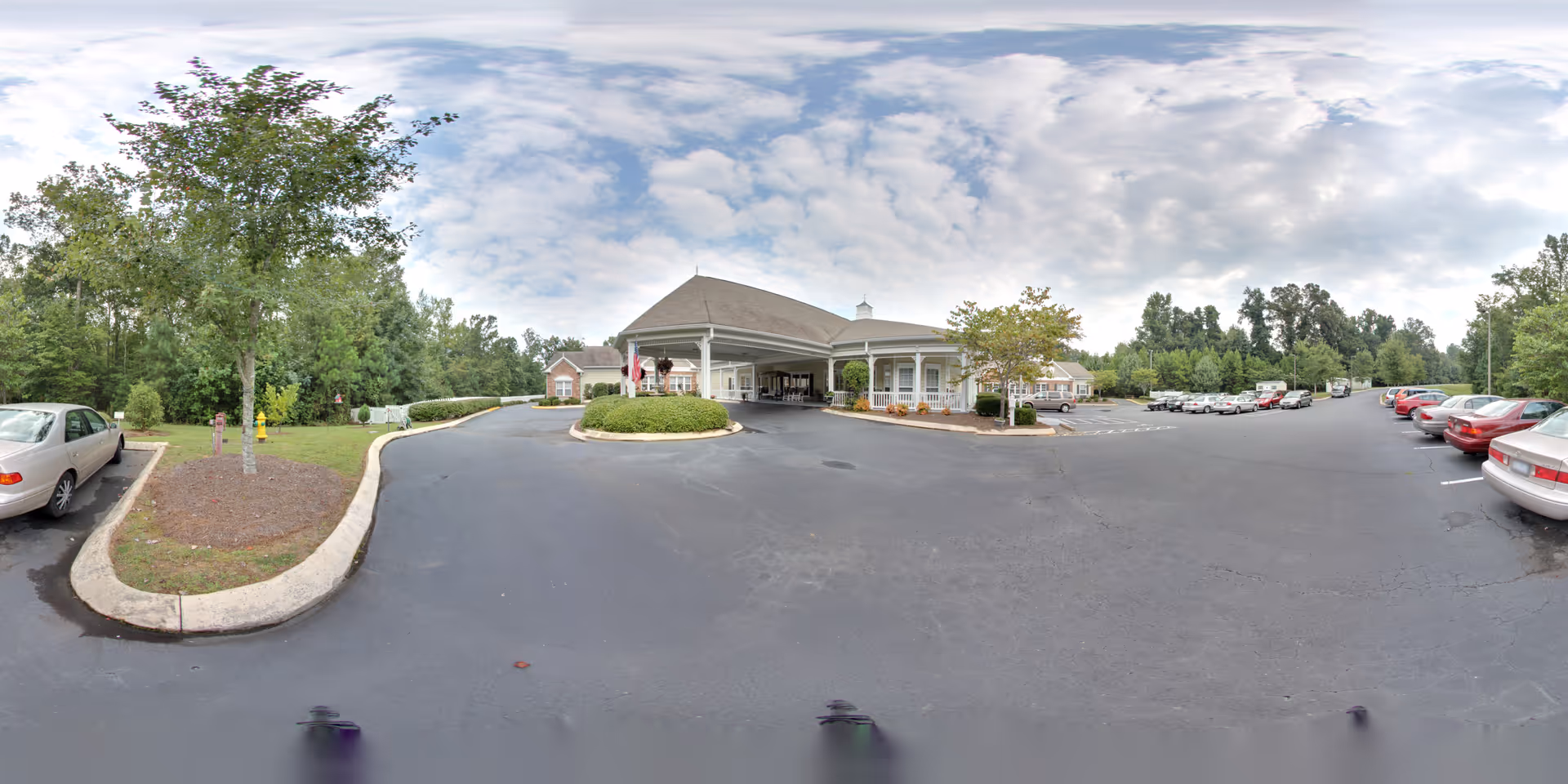 A view of the exterior entrance of Lancaster Grove Senior Living with parking areas and surrounding greenery.