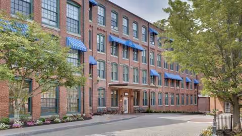 Atria Marland Place exterior brick building with blue awnings and surrounding trees.