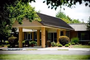 Front entrance of a single-story senior living building with a covered porte-cochere, columns, and landscaped grounds.