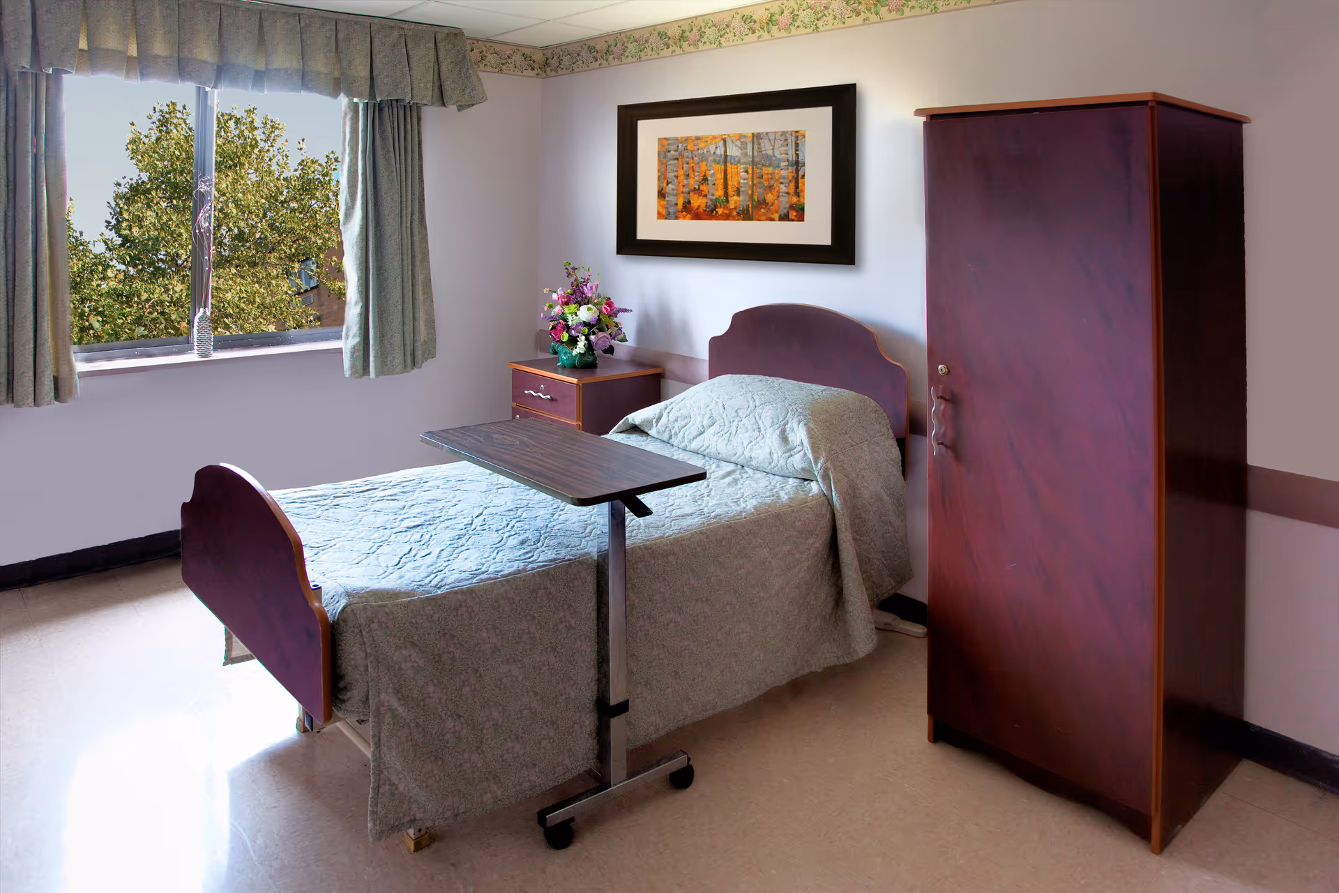 Sunlit single bed in a furnished senior living bedroom with an overbed table, nightstand with flowers, framed artwork, window and wardrobe.