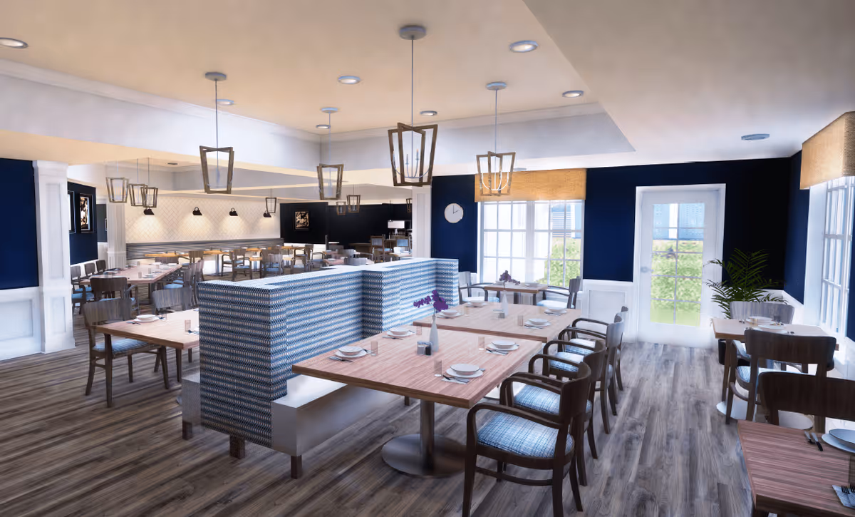 A bright and spacious dining room with wooden floors, multiple tables set with plates and utensils, cushioned chairs, and booth seating with patterned upholstery. The walls are painted dark blue with white trim, and large windows let in natural light. Modern pendant lights hang from the ceiling, and there is a door leading outside.