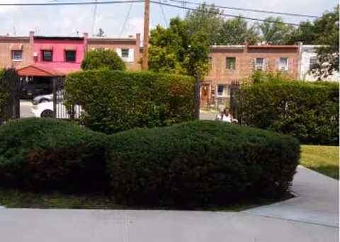 Front view of a building with trimmed hedges and a sidewalk.