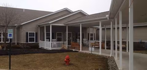 Exterior view of a senior living facility with a covered entrance and benches.