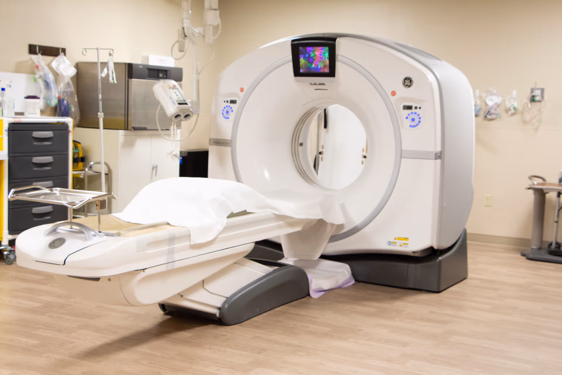 A CT scanner with a patient table in a medical imaging room.