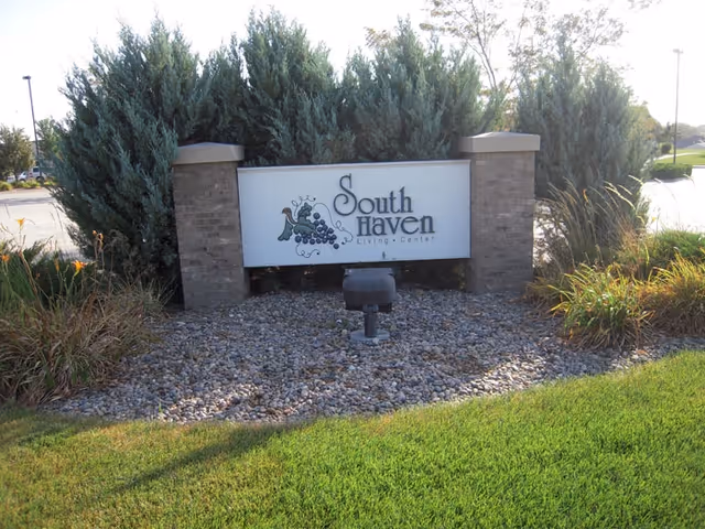 A landscaped roadside sign reading "South Haven Living Center" set between brick pillars with shrubs and grass.