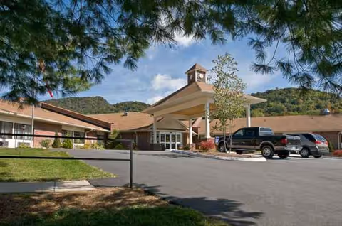 Exterior view of Life Care Center of Banner Elk with a clock-topped entrance, driveway, and cars