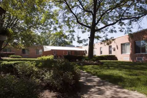 Exterior view of a brick health care facility with lawn and trees.