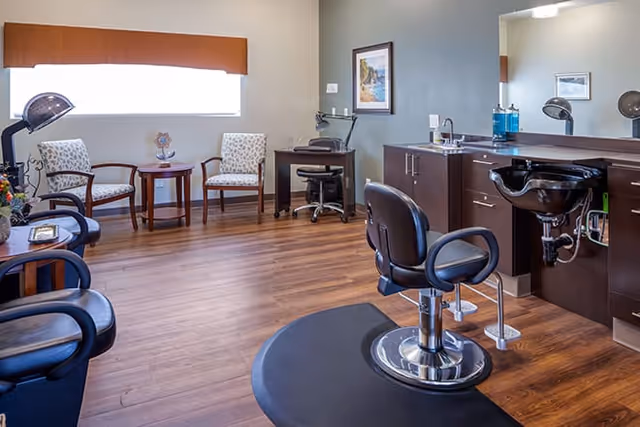 Salon-style interior with styling chairs, a hair-washing sink, mirrors, and a small seating area.