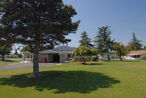 Exterior view of Castle Vista senior living facility with green lawn and trees.