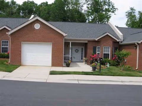 Front exterior of a red brick senior living facility with garage and landscaped entry.