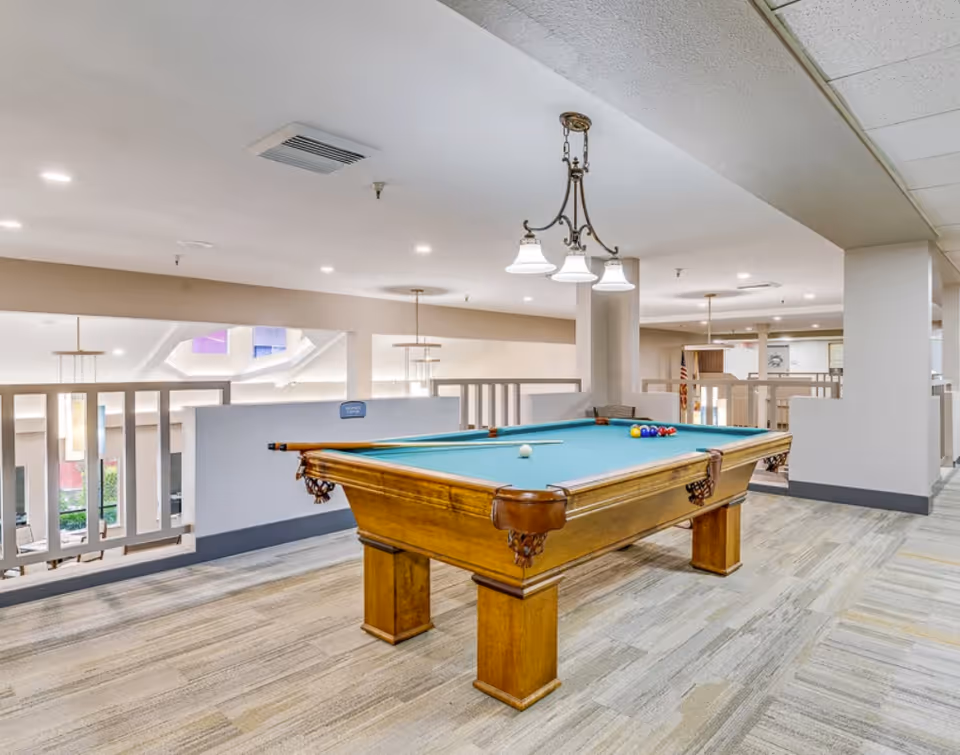 Indoor common area featuring a wooden pool table with overhead lights and open railing overlooking the lower level.