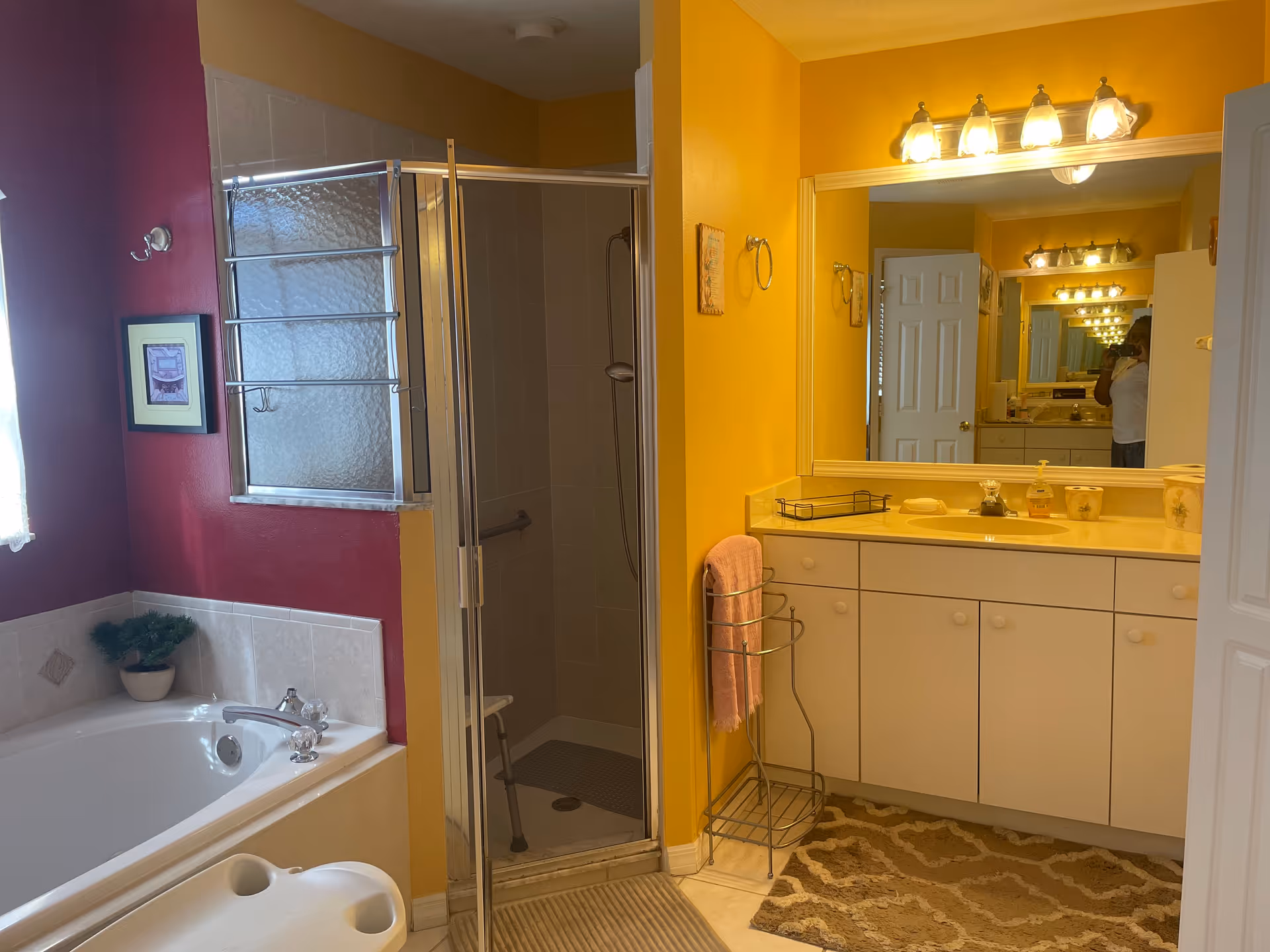 Bright yellow bathroom with a shower, tub, vanity, and large mirror.