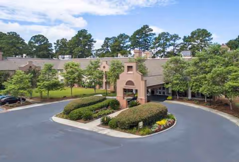 Exterior view of Savannah Square senior living facility with circular driveway and landscaped entrance.