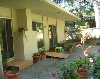 Front exterior of Bel Amor senior living facility with potted plants along walkway.