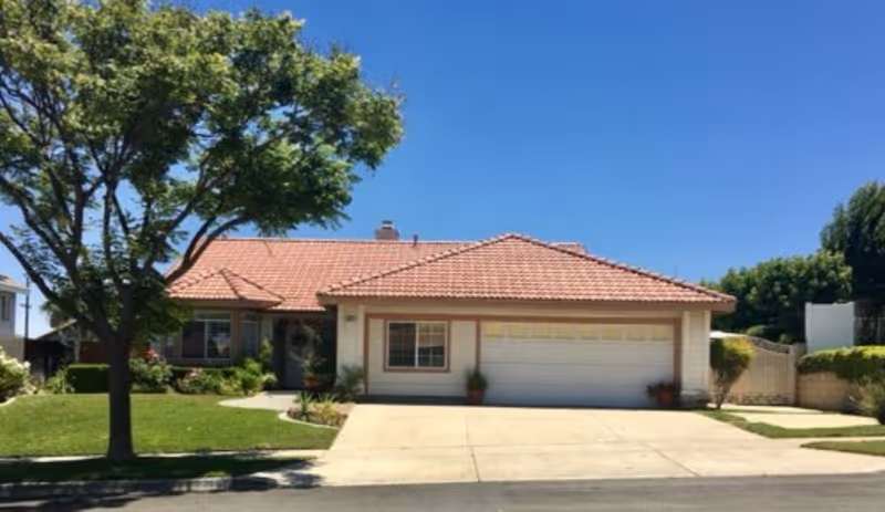Single-story house exterior with a tiled roof, front yard, and two-car garage.