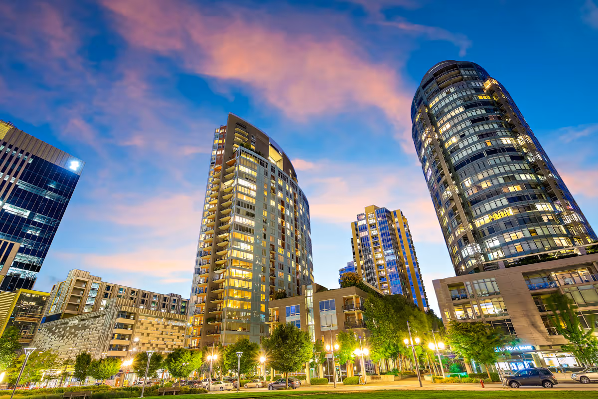 Evening view of modern high-rise residential buildings with lit windows beneath a pink-blue sky.