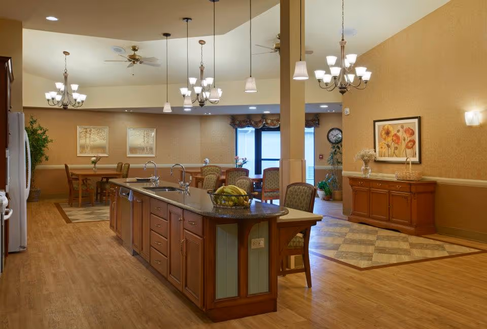 Open communal dining area with a large kitchen island, pendant lights, multiple dining tables and warm wood decor.