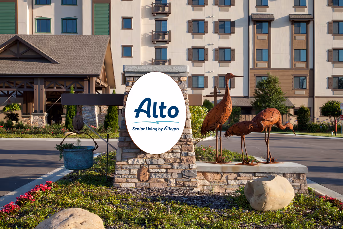 Stone entrance sign reading 'Alto Senior Living by Allegro' with metal bird sculptures and the facility building behind it.