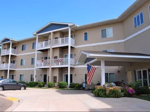 Exterior view of Pine Manor Estates senior living building with balconies and an American flag.