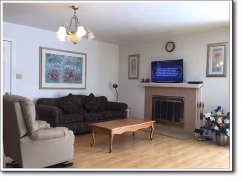 A cozy living room with a sofa set, coffee table, fireplace, and TV.