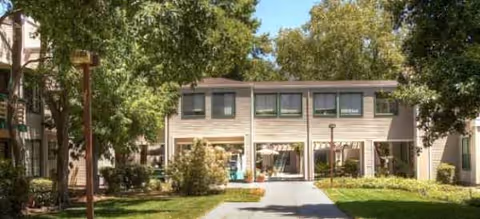 Two-story senior living building with a central walkway and green lawn.