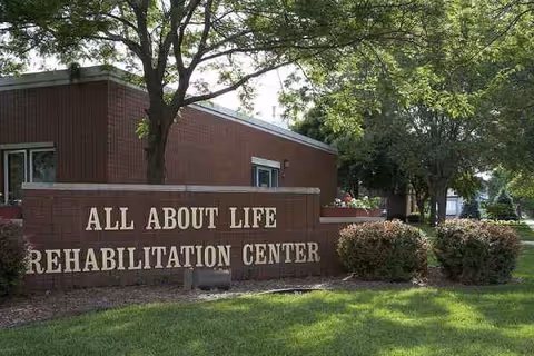Exterior view of a brick rehabilitation center with a large sign and green lawn.