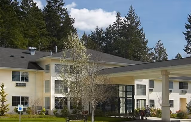 Exterior view of Maple Glen Assisted Living building with trees and covered entrance