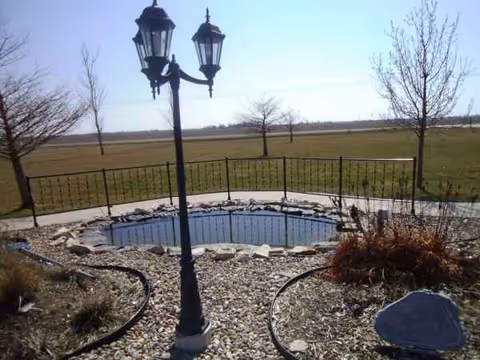 Outdoor courtyard with a decorative lamp post, gravel paths, and circular stone feature