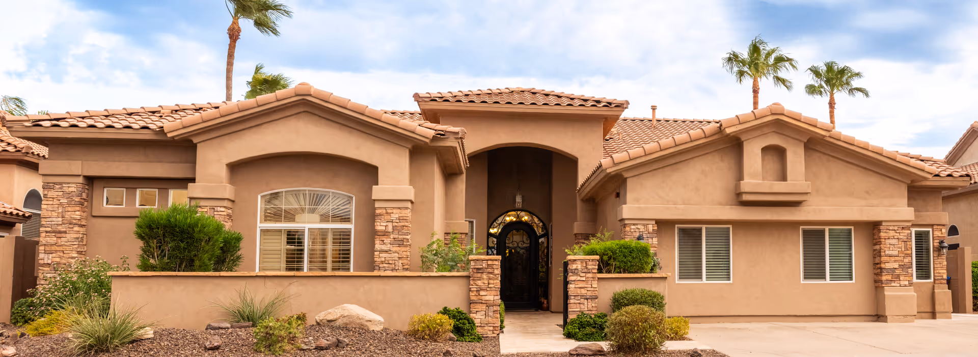 A single-story beige stucco senior living facility with arched entry and desert landscaping.