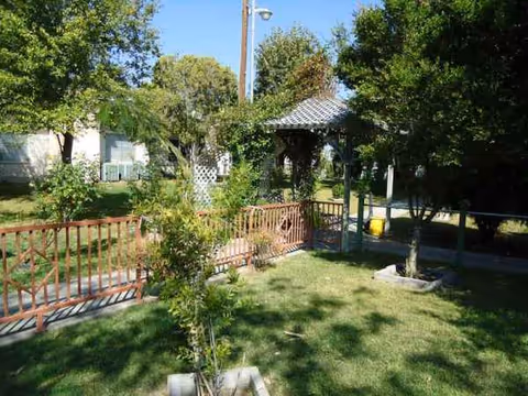 Outdoor garden area with gazebo, trees, and a grassy lawn at a nursing home.