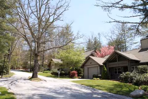 Exterior view of Chestnut Hill of Highlands showing a driveway, trees, and a clubhouse-style building.