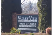 Outdoor sign for Valley View Retirement Village and Rock of Ages Mennonite Home surrounded by trees and flowers.