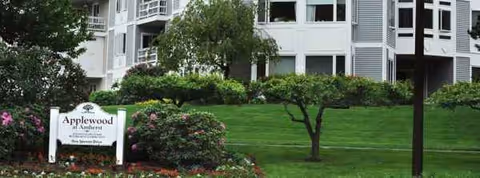 Exterior view of Applewood at Amherst with green lawn, trees, and entrance sign.
