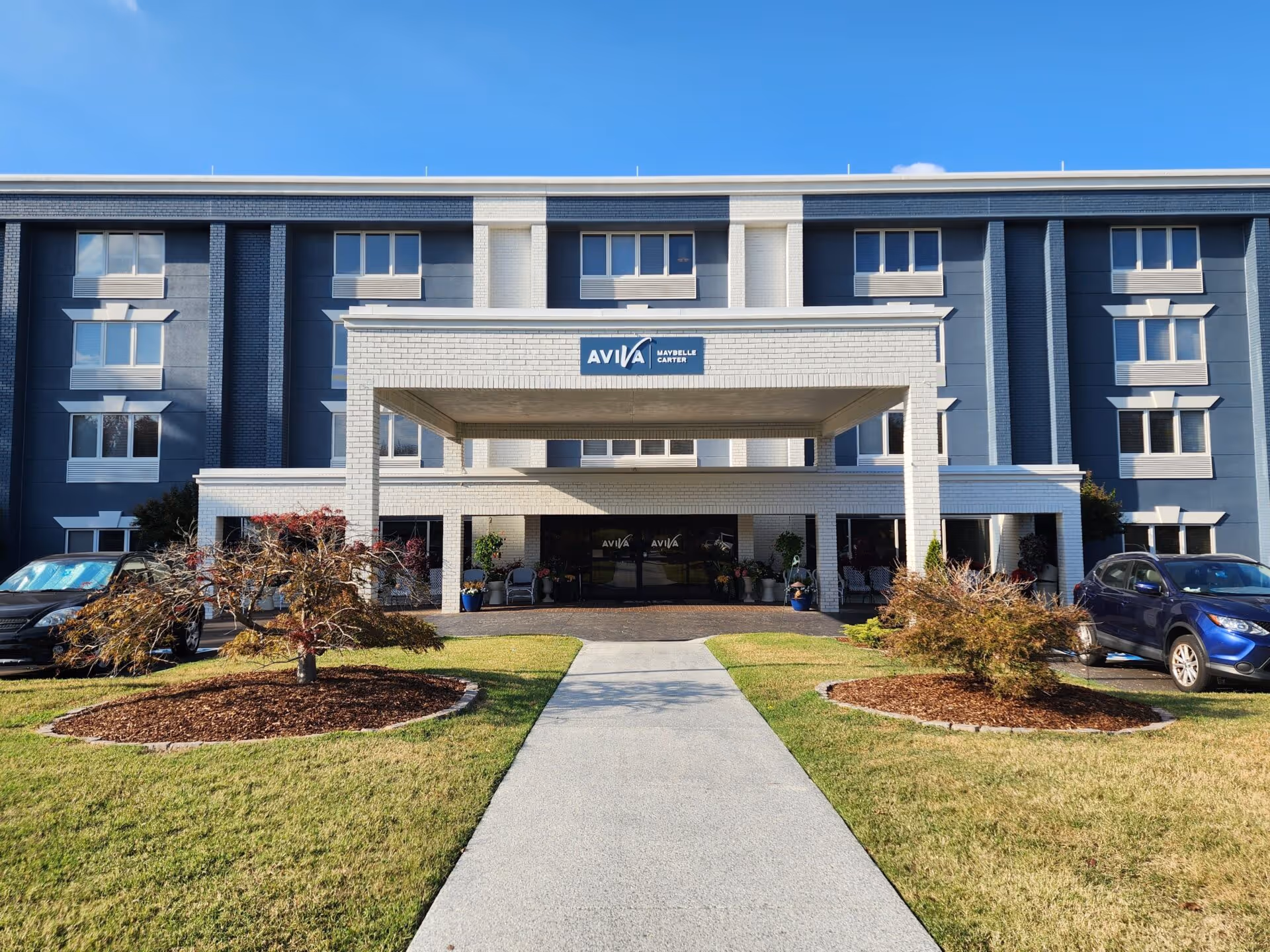 Front entrance of a multi-story senior living building with a covered driveway and AVIVA Maybelle Carter sign.