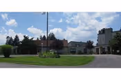 Exterior view of a single-story senior living facility building named Thornwald Home, with a driveway, green lawn, trees, and a partly cloudy sky.