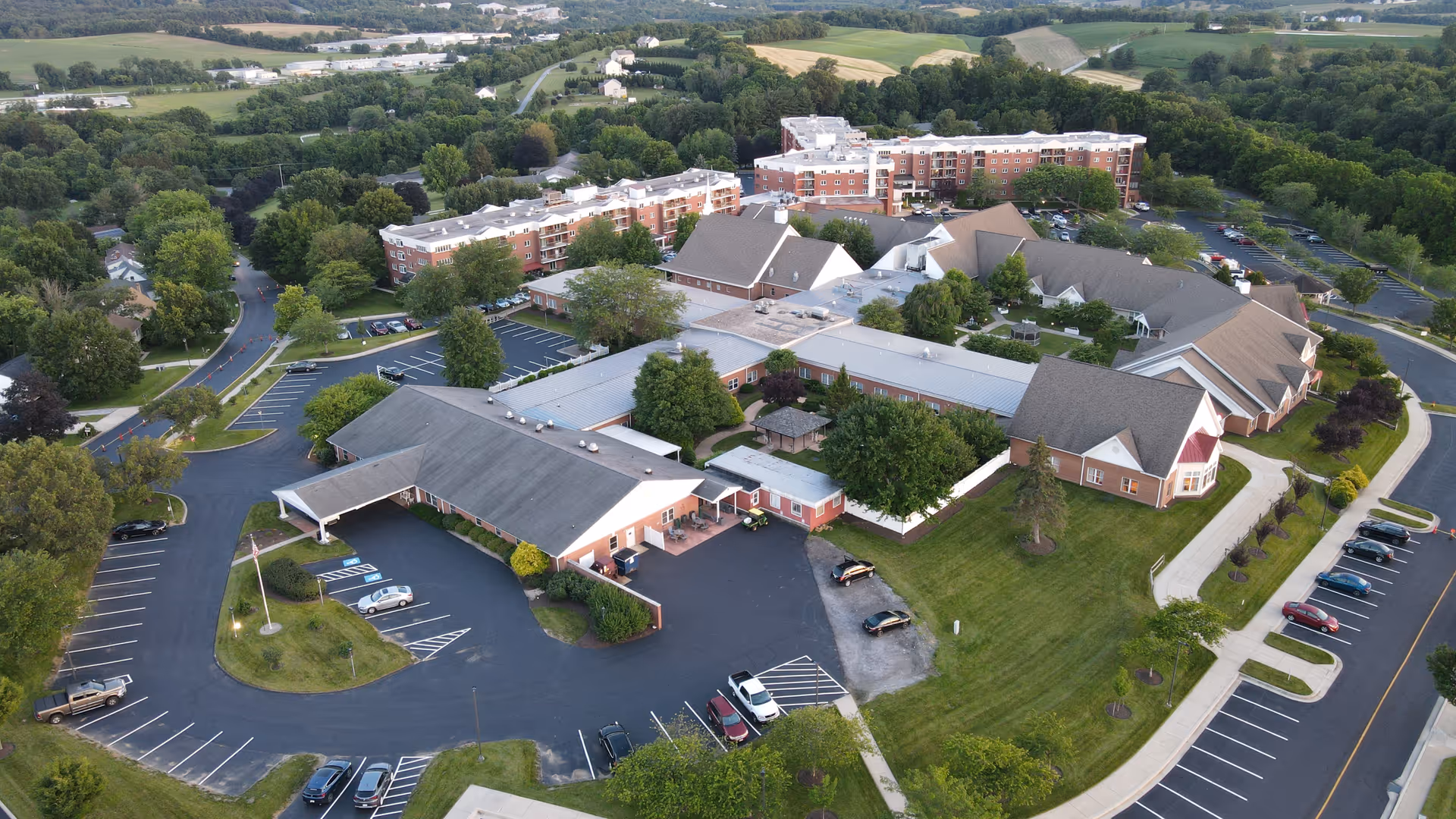 Aerial view of Carroll Lutheran Village campus with multiple connected brick buildings, parking lots, green lawns and surrounding countryside.