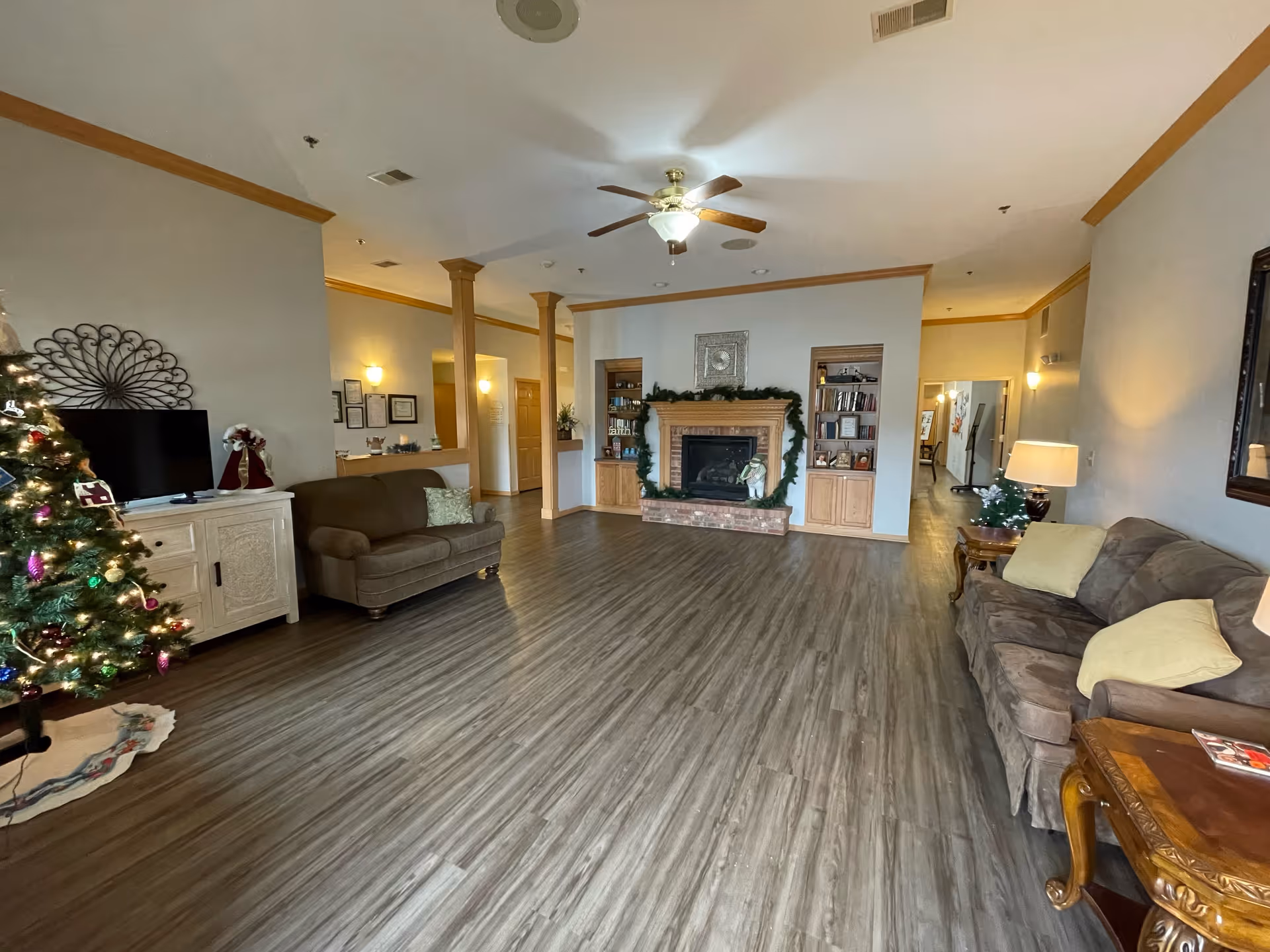 Spacious living room in a senior facility with sofas, fireplace, and Christmas tree.