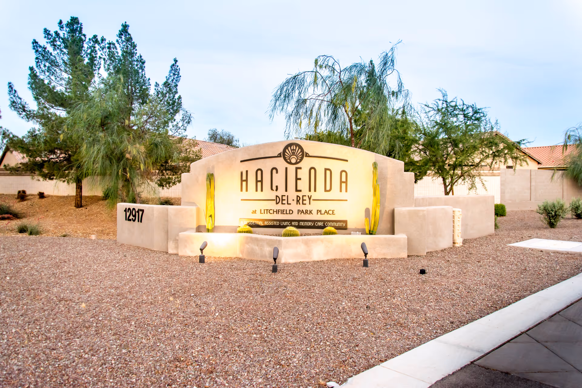 Exterior view of Hacienda Del Rey entrance sign with desert landscaping and gravel surroundings