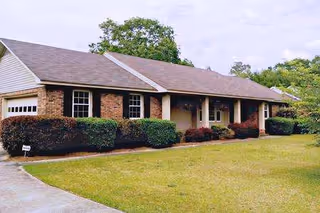 Single-story brick senior living home with a front porch and green lawn.