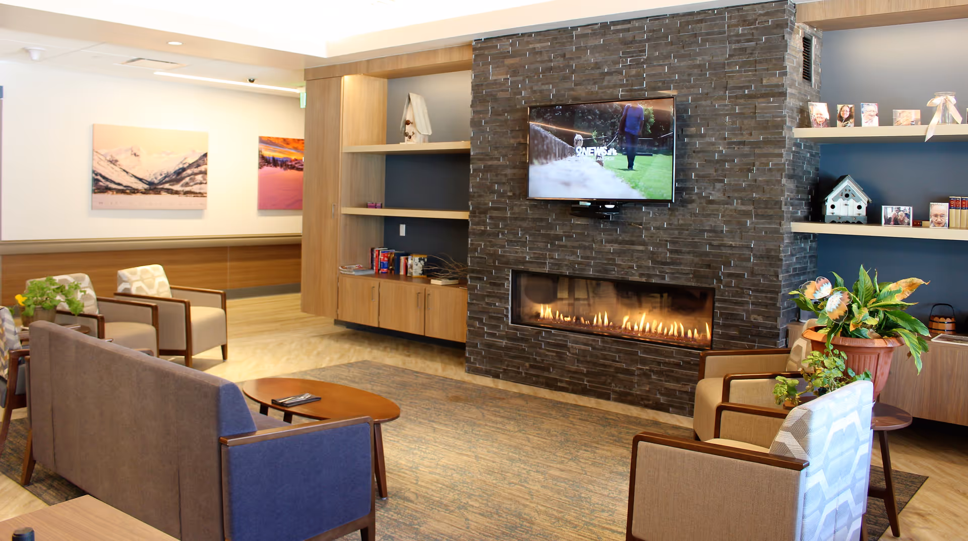 Comfortable lounge area with seating, a stone fireplace and a wall-mounted TV.