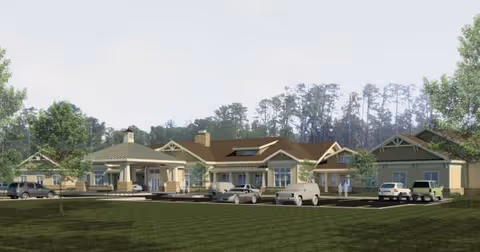 A single-story senior living facility with parked cars, a curved driveway, and green lawn.
