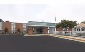 Exterior view of Charlottesville Health & Rehabilitation Center showing a brick building with a covered entrance, a driveway, and a white gazebo on the right side.