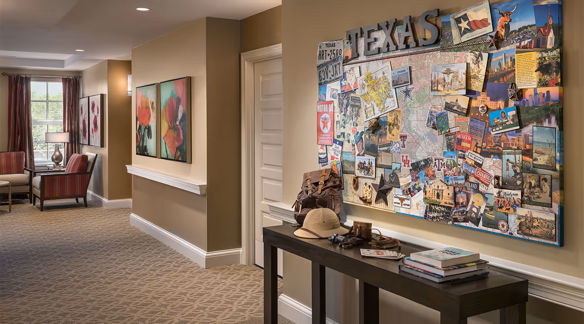 Hallway seating area with a console table and a large Texas-themed bulletin board on the wall.
