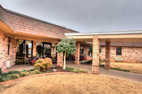 Exterior view of Conway Healthcare & Rehab entrance with brick columns, walkway, and greenery.