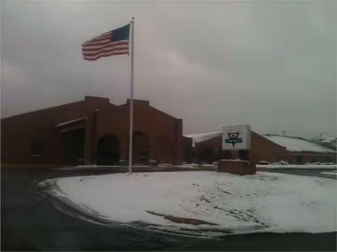 Exterior view of Cuba Manor Inc building with American flag in snowy parking lot