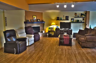 Open living room with multiple recliners and sofas arranged around a coffee table, TV, and fireplace on wood flooring.