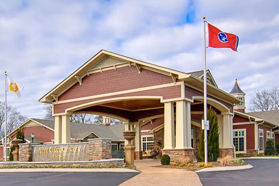 Front entrance canopy and sign of the Life Care Center building with flags flying in front.